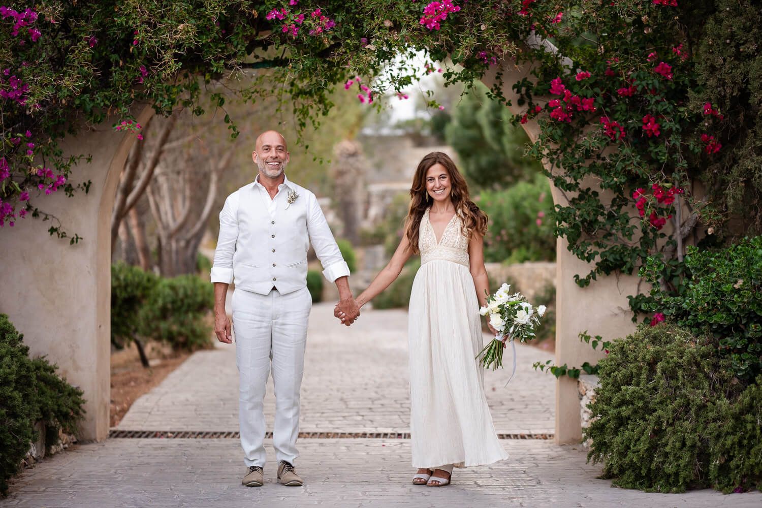 The newlyweds walking hand in hand through the Cycladic estate