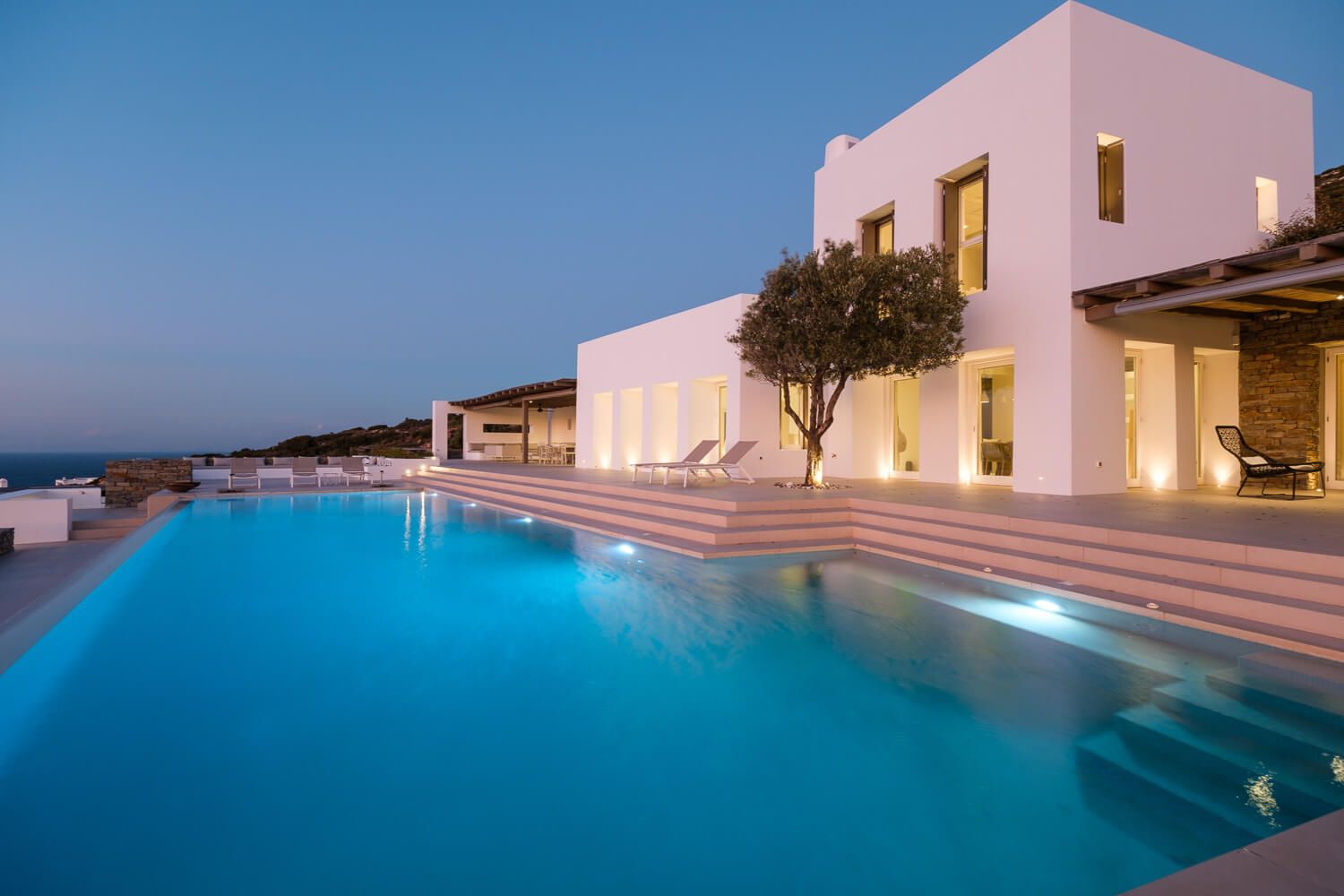 Elegant Cycladic villa with illuminated pool at dusk, photographed by Michael Salis.
