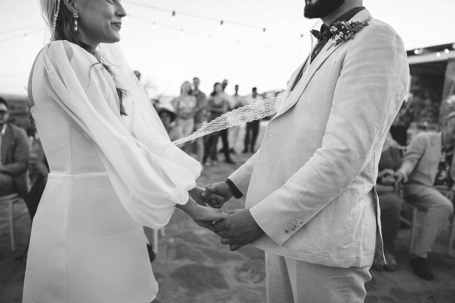 Bride and groom holding hands during their heartfelt symbolic vows in Greece