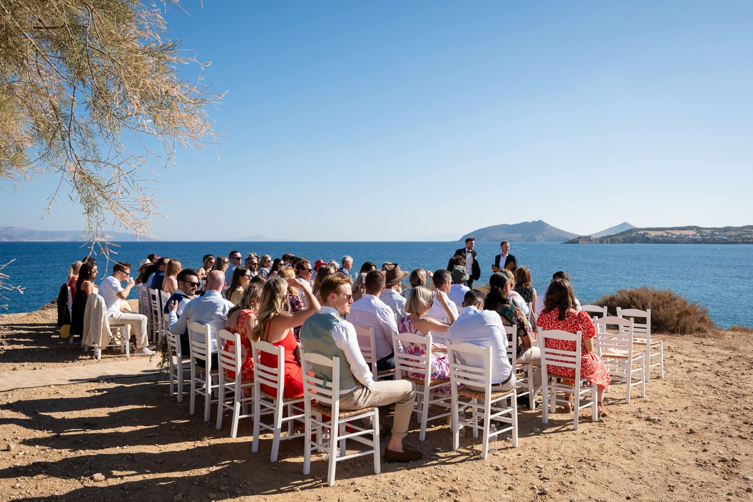 Guests taking their seats by the sea for a symbolic wedding ceremony