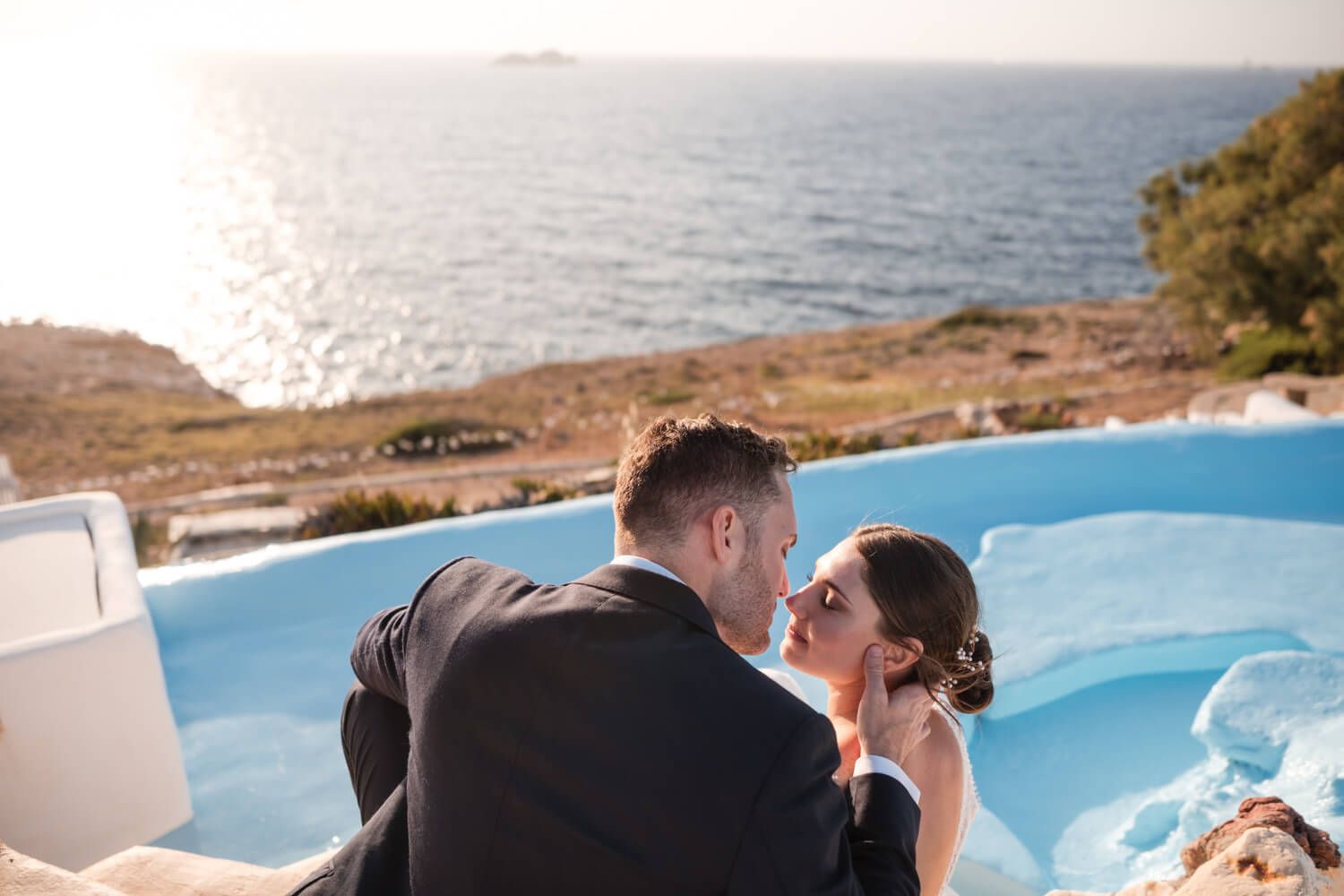 Lizzy and Cody embracing with the beautiful Paros landscape behind them