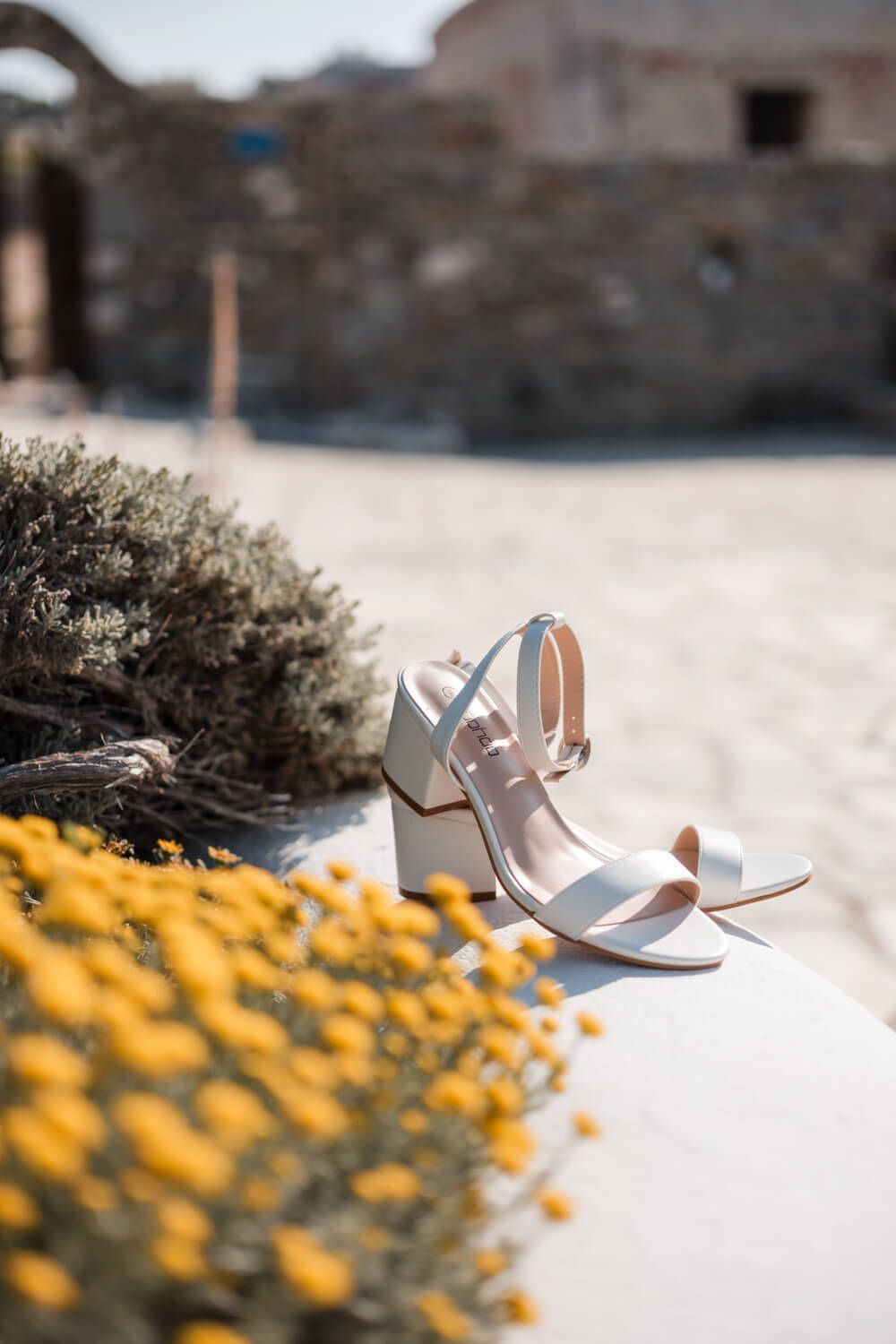Bridal shoes resting on a stone bench at a Greek island villa