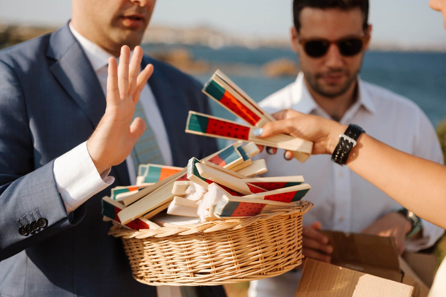 Guests sharing hand fans before a wedding ceremony in Greece