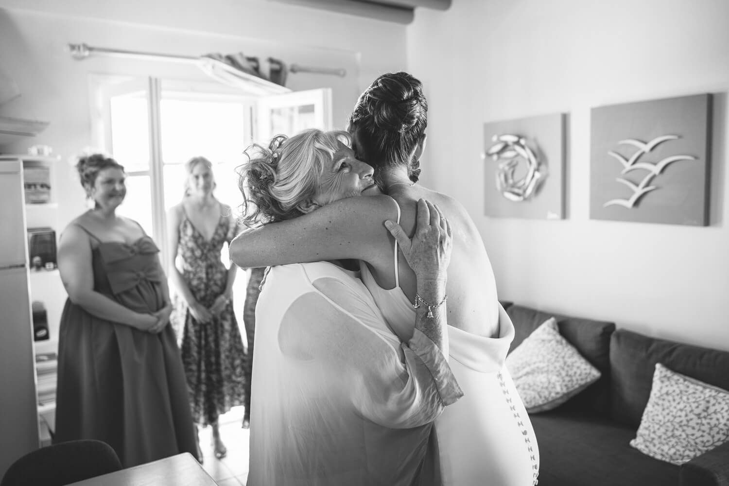 A black and white photo showing candid moments of wedding preparations with bride and mother hugging