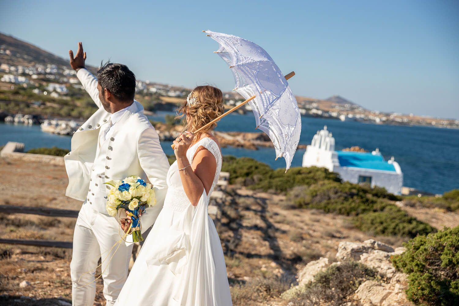 Newlyweds waiving at guests in front of Pyrgaki chapeli in Paros Greece