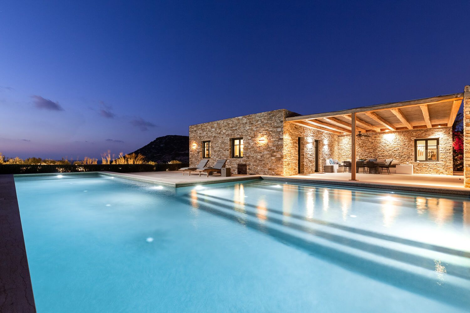 Luxury villa with illuminated pool at dusk, featuring stunning Mediterranean views in Antiparos.