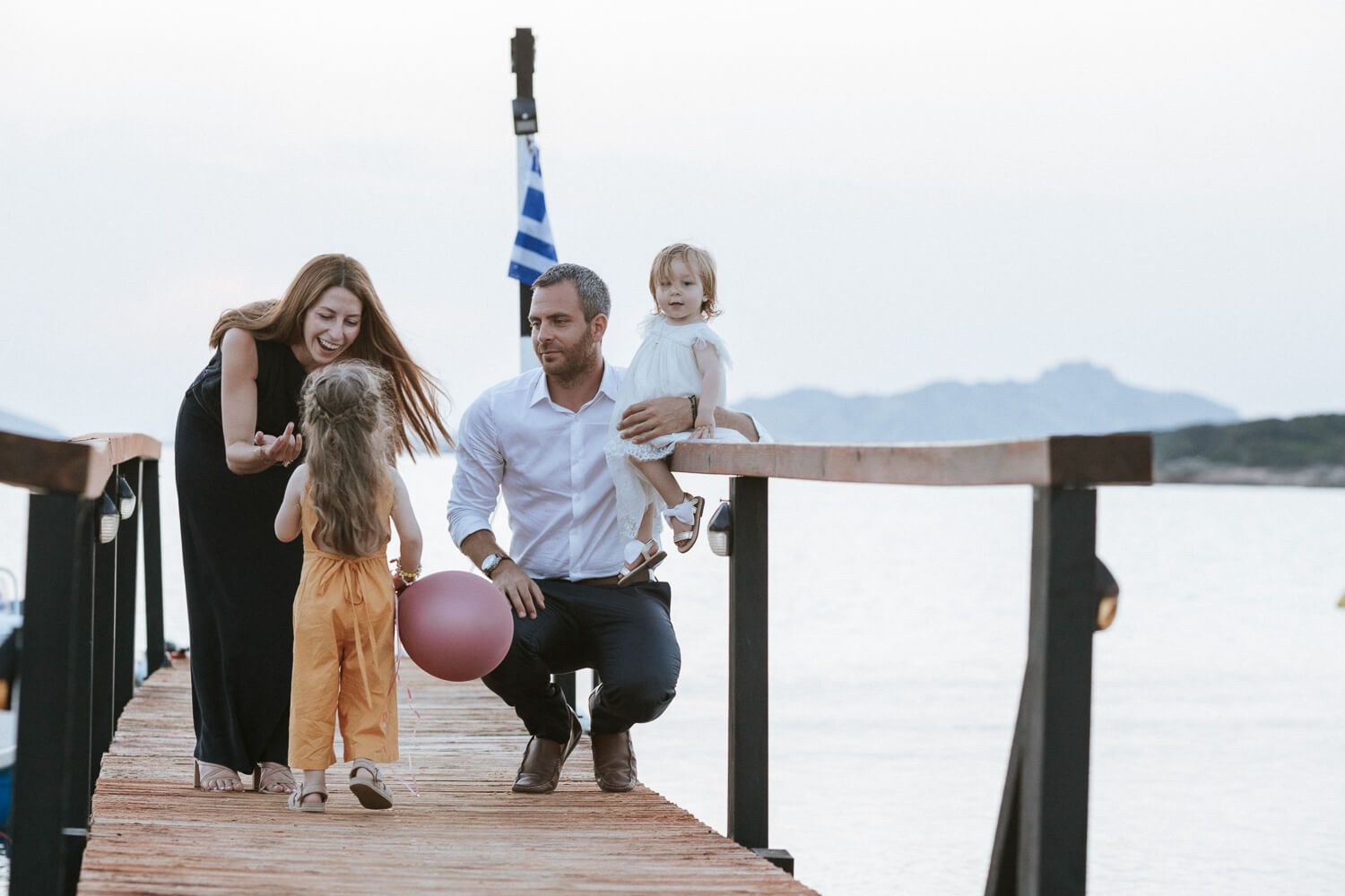 Γονείς αγκαλιάζουν τα παιδιά τους με φόντο το ηλιοβασίλεμα στο Siparos