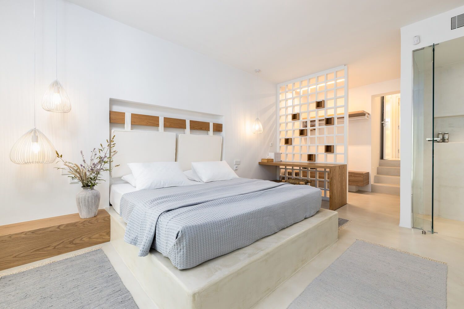 Modern minimalist bedroom with white walls, wood accents, and built-in lighting features showcases a clean design.