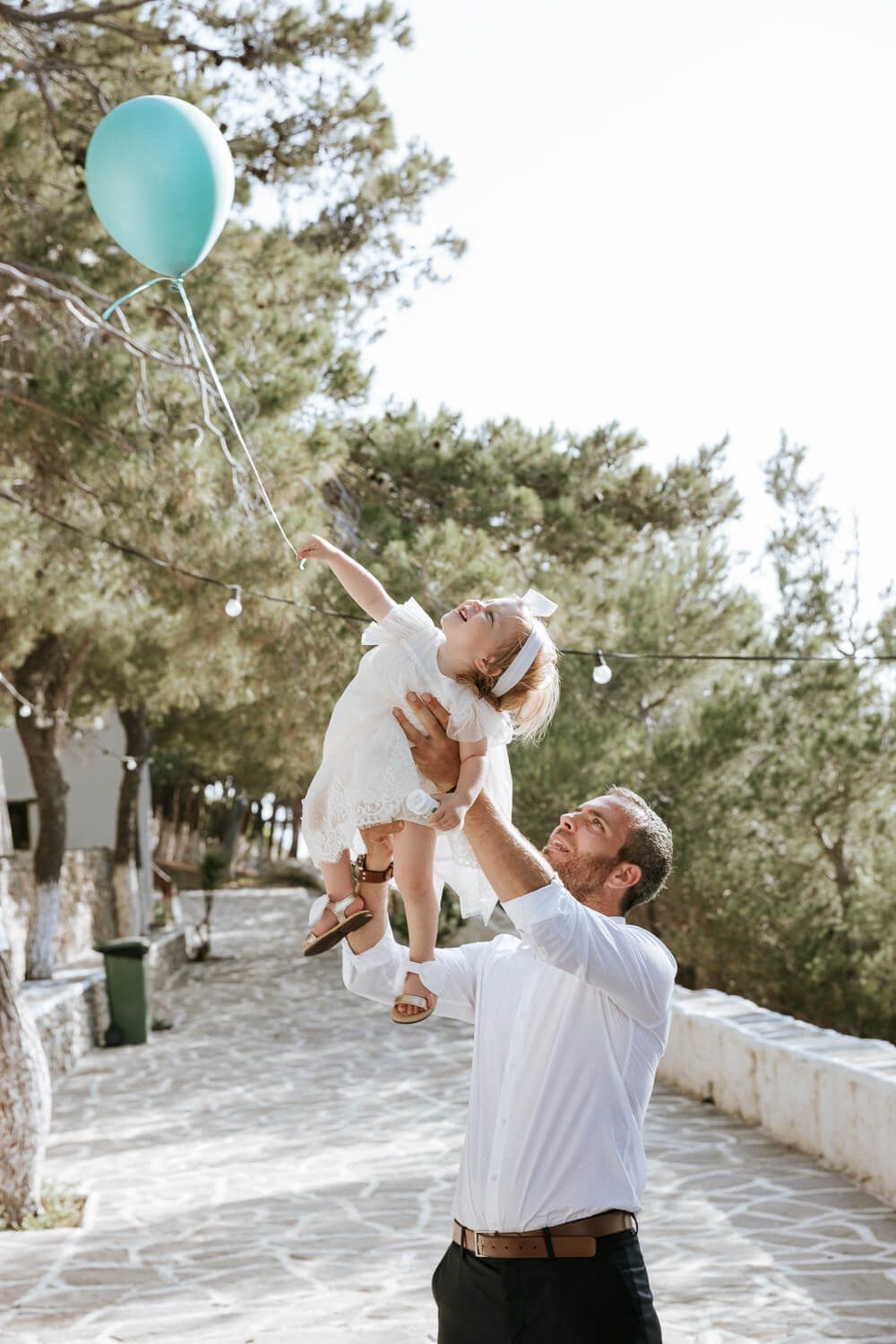 Ο μπαμπάς σηκώνει ψηλά το μωρό του με φόντο τη θάλασσα της Πάρου