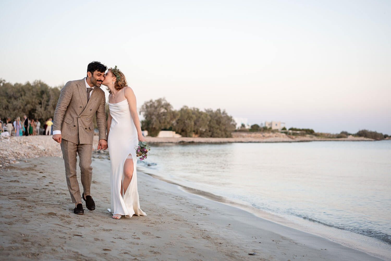 Newlyweds walking hand in hand along the scenic Paros coastline