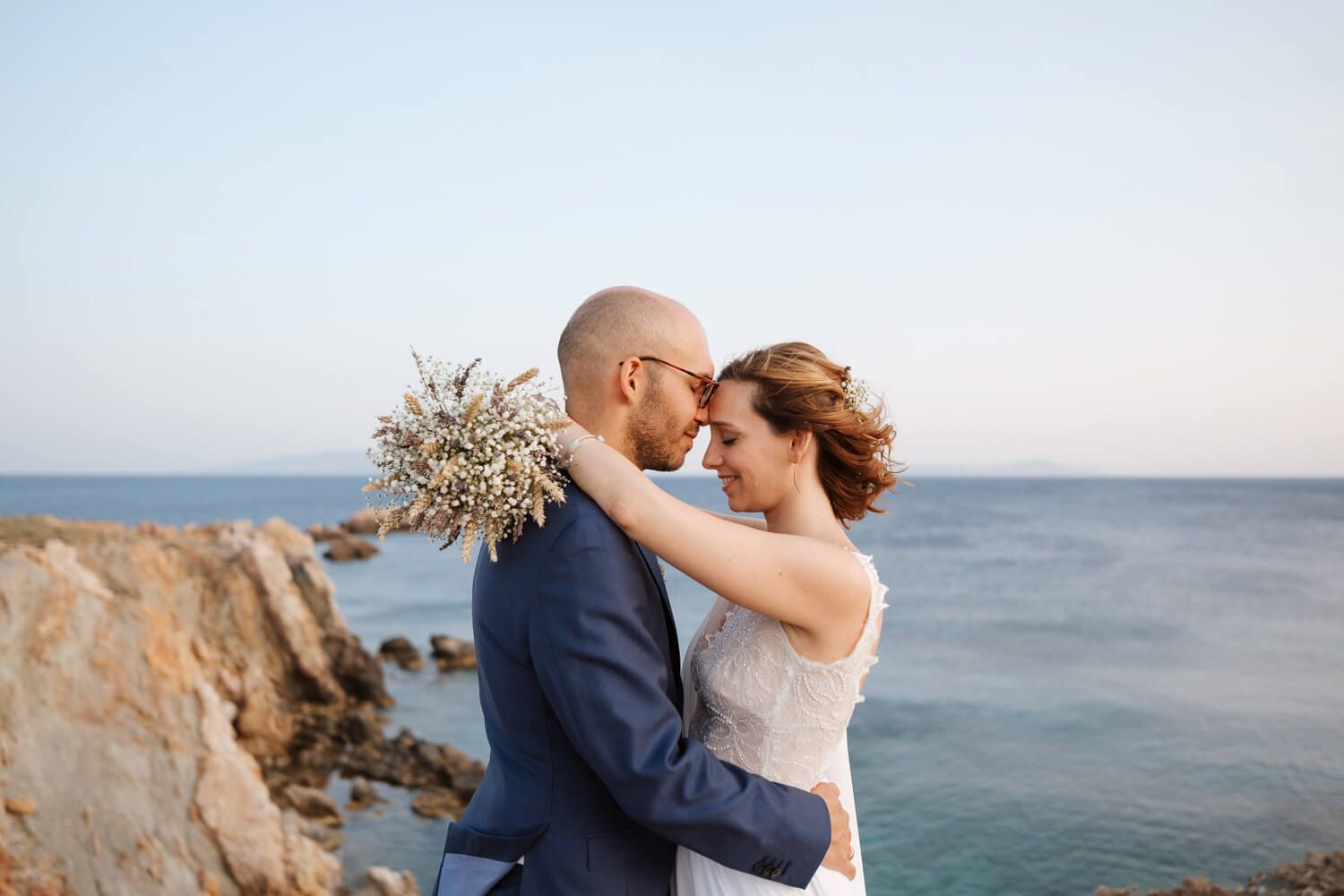Romantic newlywed portraits overlooking the deep blue Aegean Sea in Paros