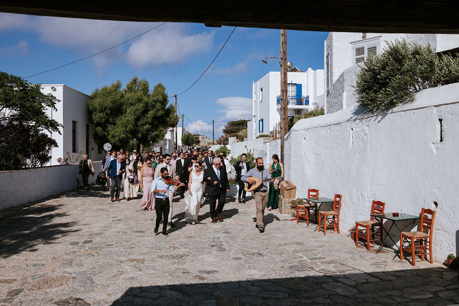 The bride is heading to the church acompanied by local musicians in Aigiali Amorgos
