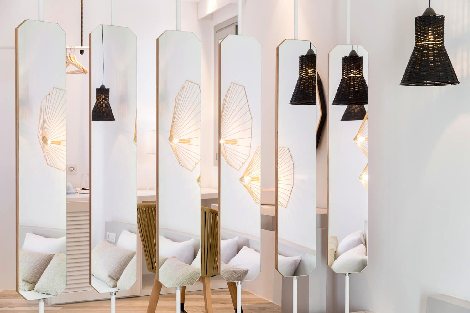 Bright white interior with tall gold-framed mirrors and decorative black pendant light fixtures.