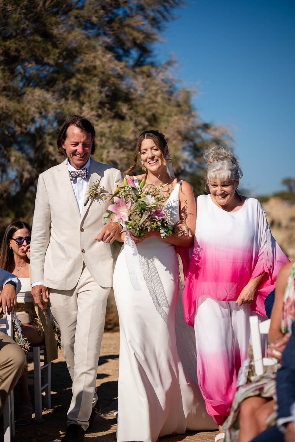 Bride Jess walking down the rocky aisle with the Aegean in the background