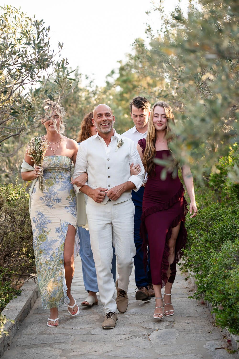 Groom Dean entering the ceremony area by the chapel at Petra Farm Paros