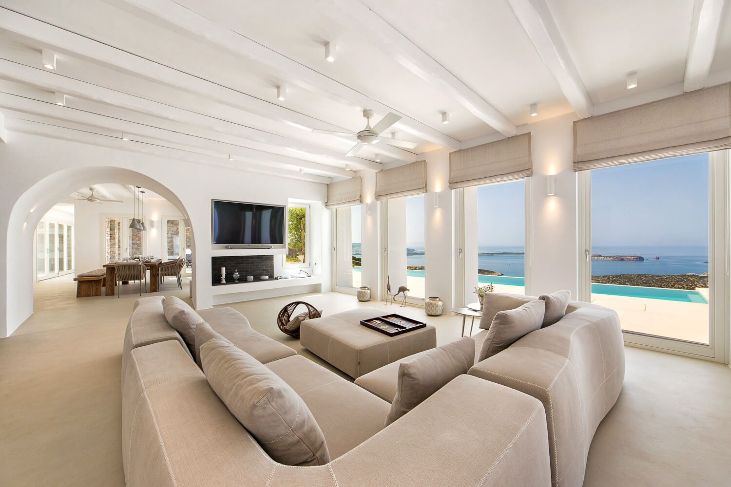 Luxurious living room with beamed ceilings, sectional sofa, fireplace, and stunning ocean views.