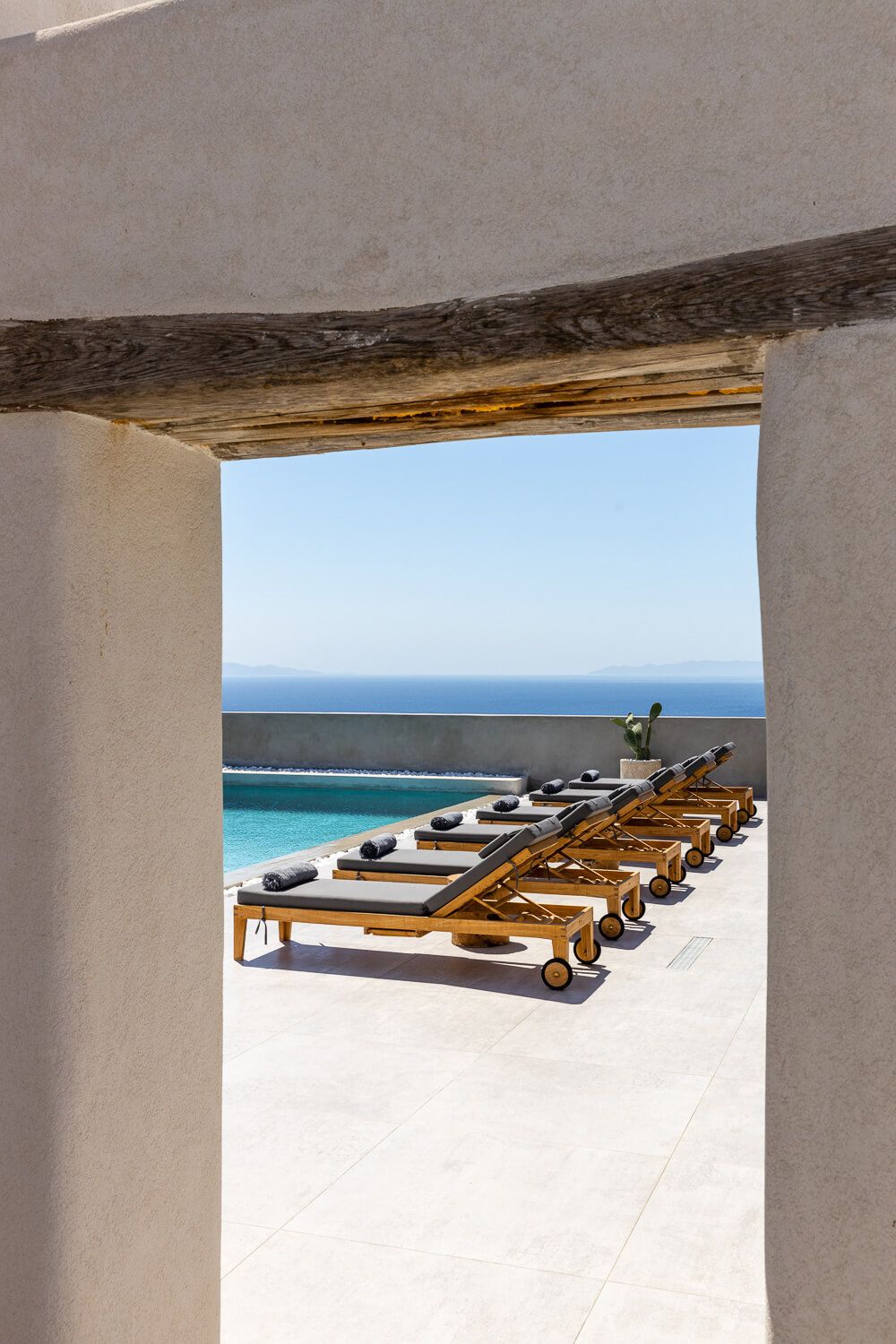 Luxury beach lounge chairs through as door, overlooking the aegean sea