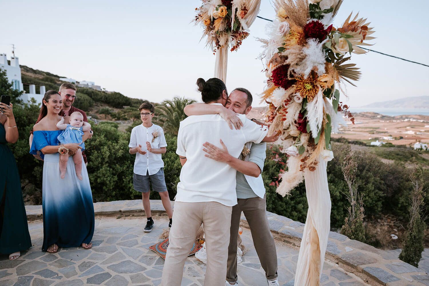 Groom Rady waiting under a rustic wooden arch in Isterni Paros