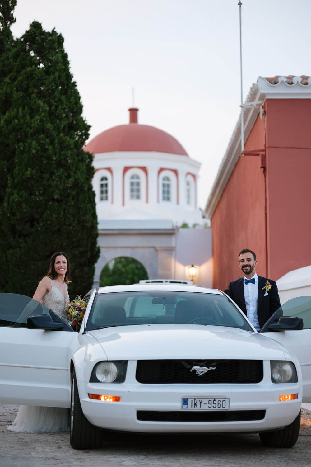 Το ζευγάρι ποζάρει μπροστά στη Ford Mustang μετά το γάμο στον Ναό της Αγίας Παρασκευής