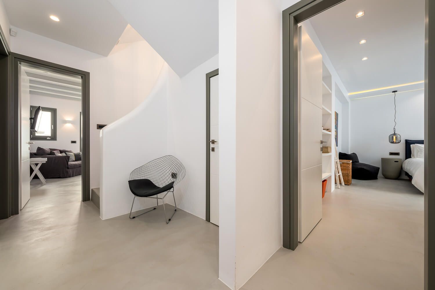 Minimalist hallway with white walls, grey doors, and recessed lighting connects multiple interior rooms.