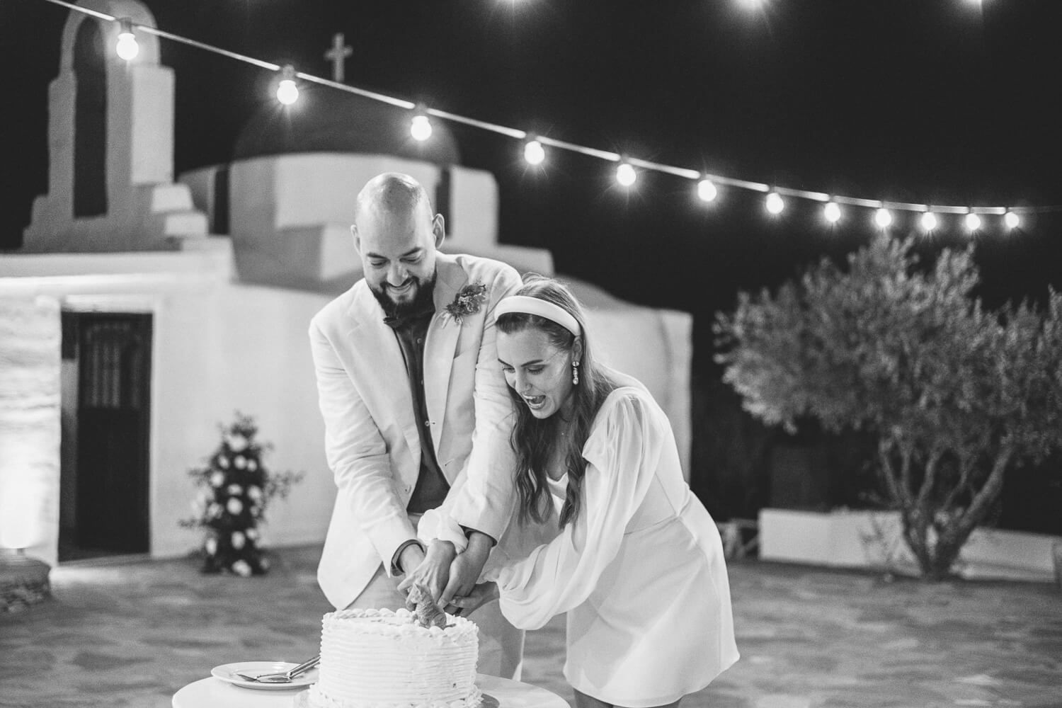 Couple sharing wedding cake during a wedding reception in The Secret View Paros