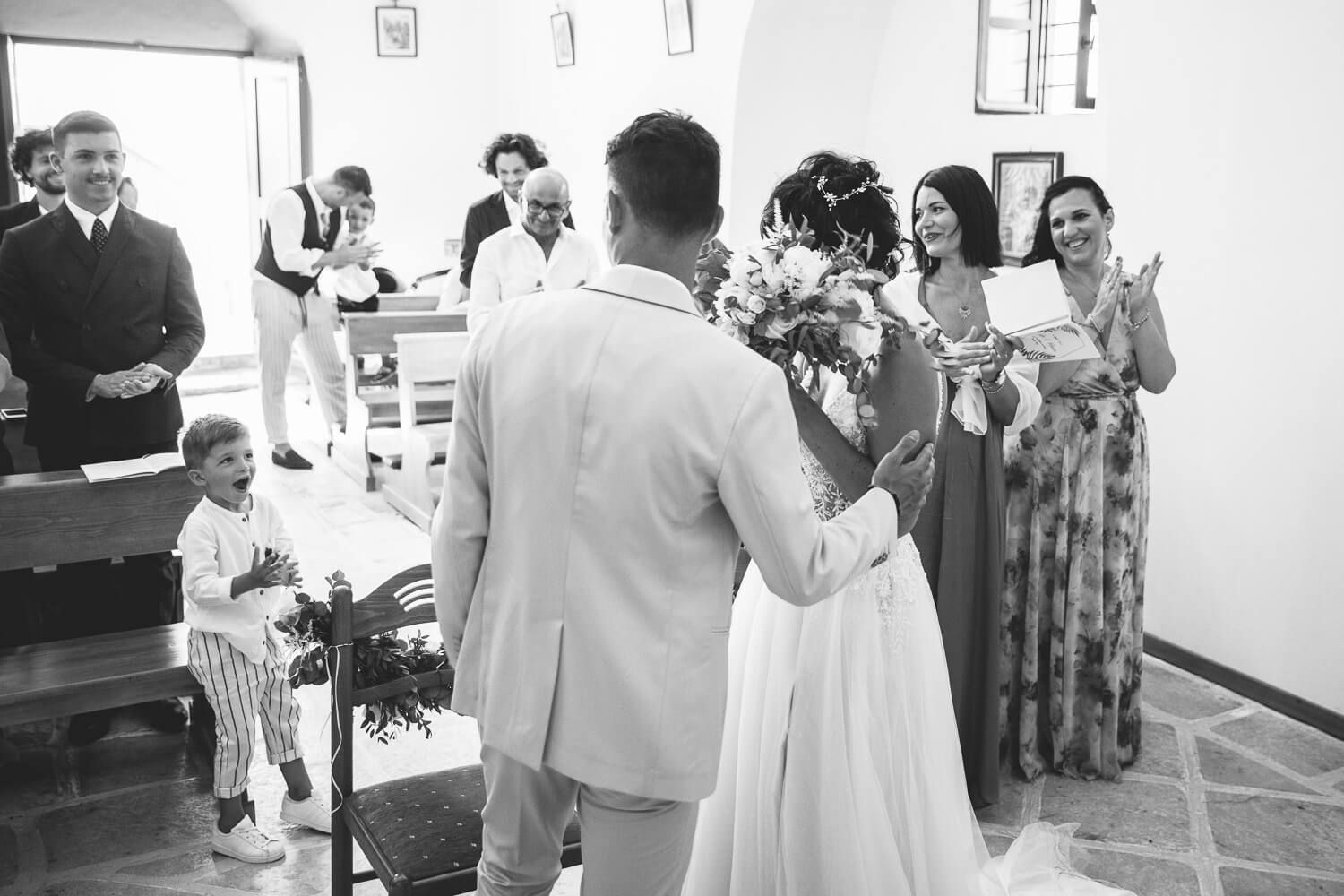 Newlyweds smiling at each other under the stunning architecture of St. Antony's church in Paros