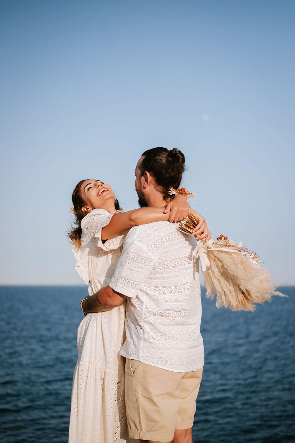 Meli and Rady hugging bofore the wild Cycladic landscape during their engagement session