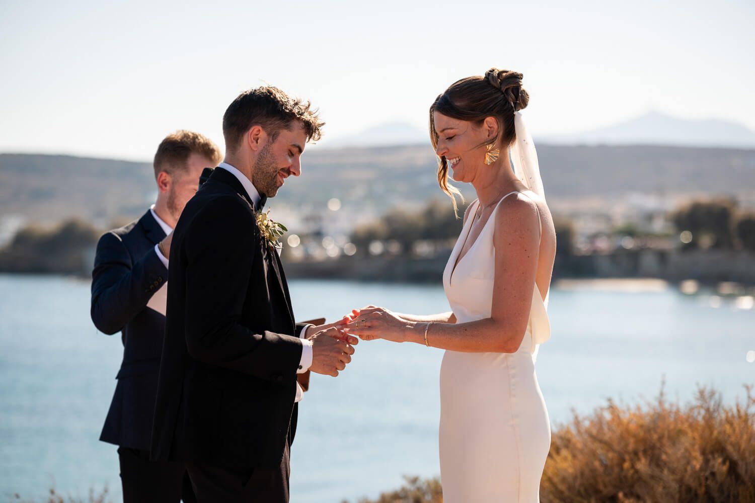 Jess and Daniel exchanging rings with waves crashing behind them