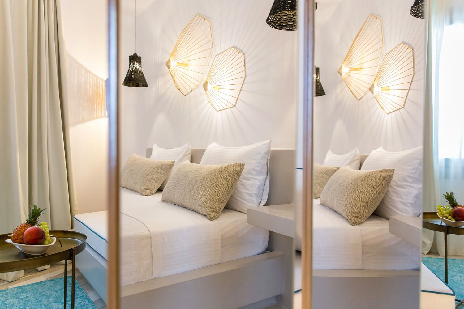 Modern bedroom interior with white bedding, decorative butterfly wall lamps, and a cozy window seating area.