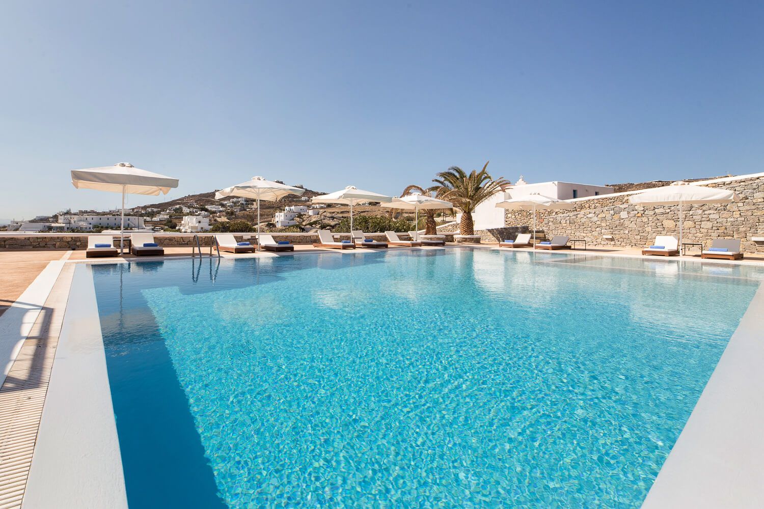 Expansive main swimming pool reflecting minimalist Mykonian architecture