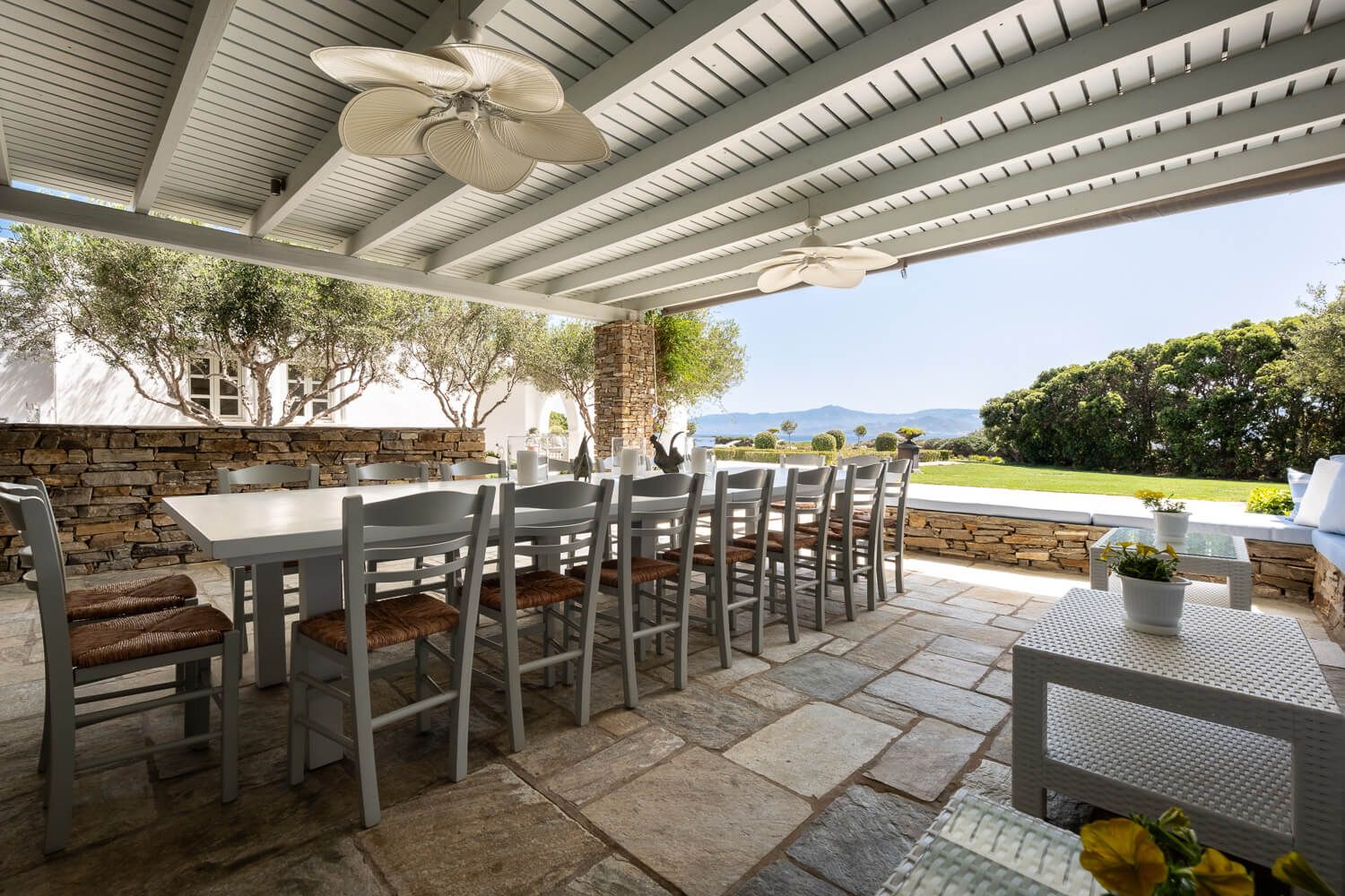 Covered outdoor patio area with wooden beams and white ceiling features comfortable seating and dining furniture.