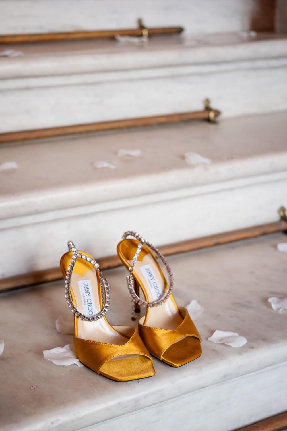 Wedding shoes on staircase with flower petals all around