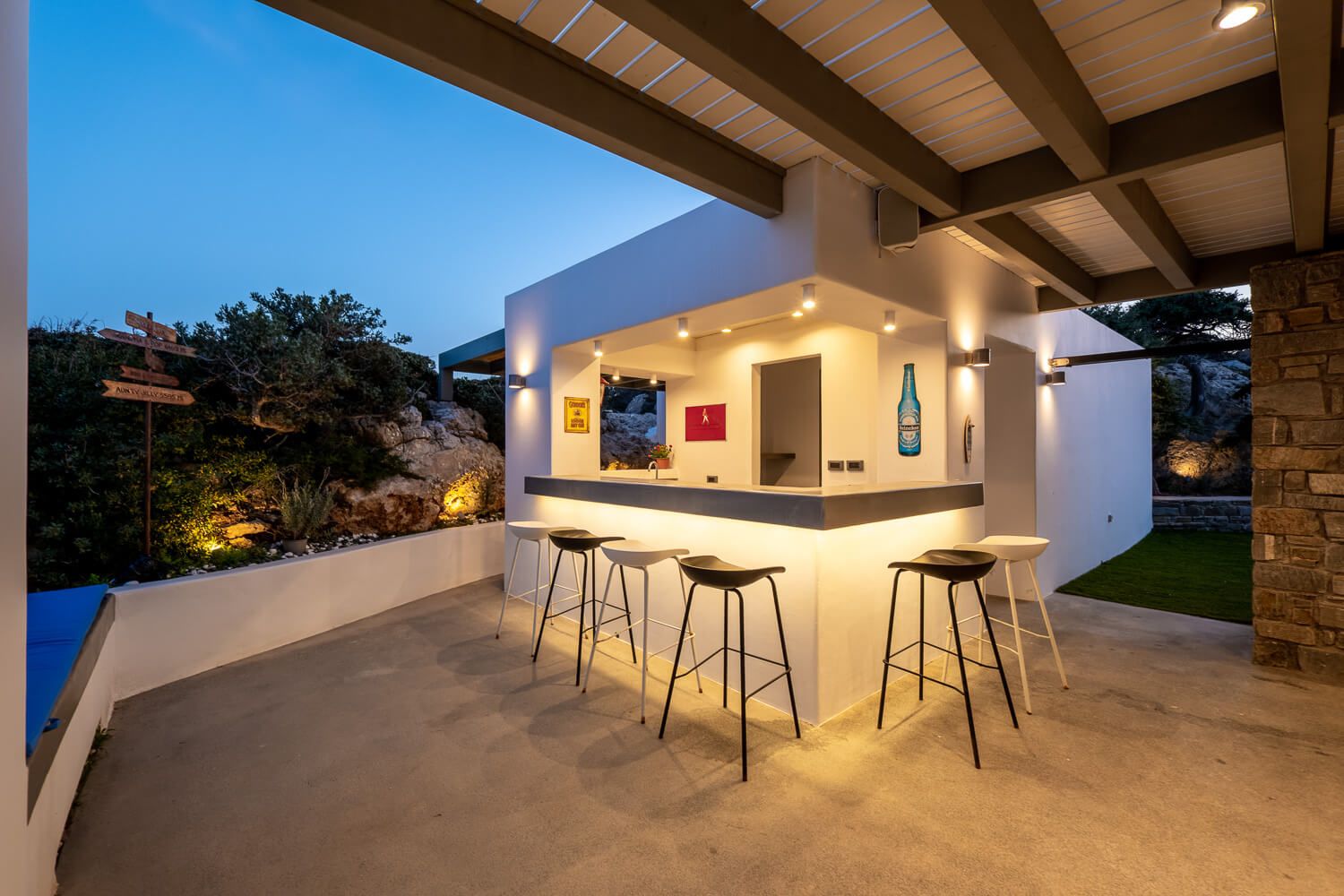 Modern outdoor patio with built-in seating and warm lighting features a sleek bar area and minimalist design elements.