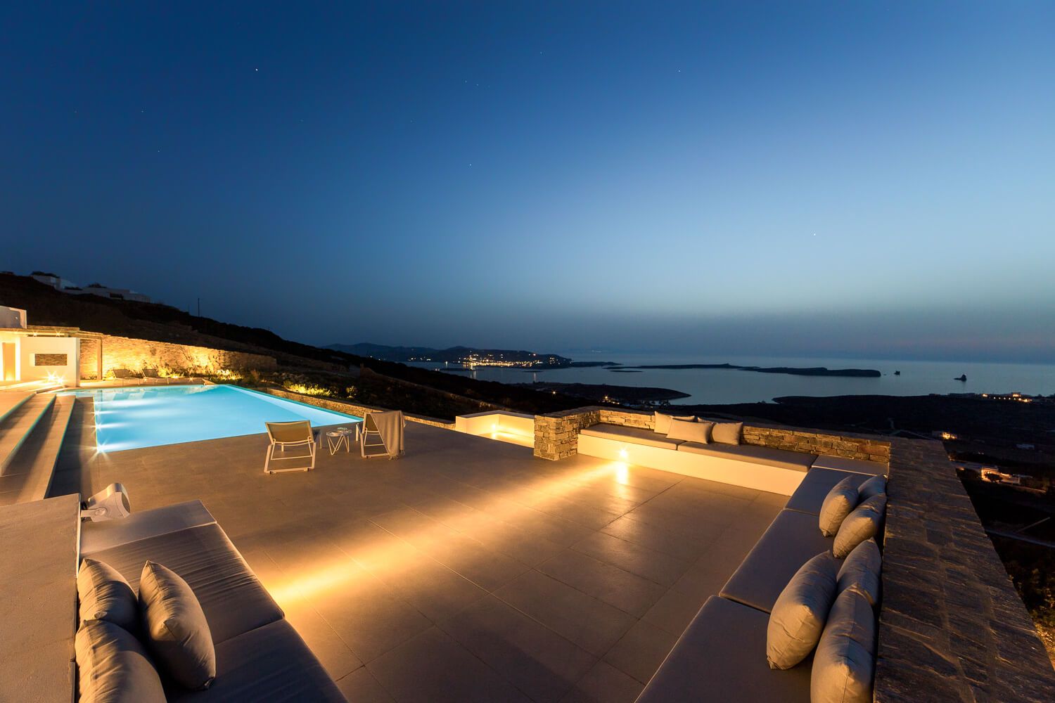 Contemporary exterior lounge setups with breathtaking Greek sea views at dusk