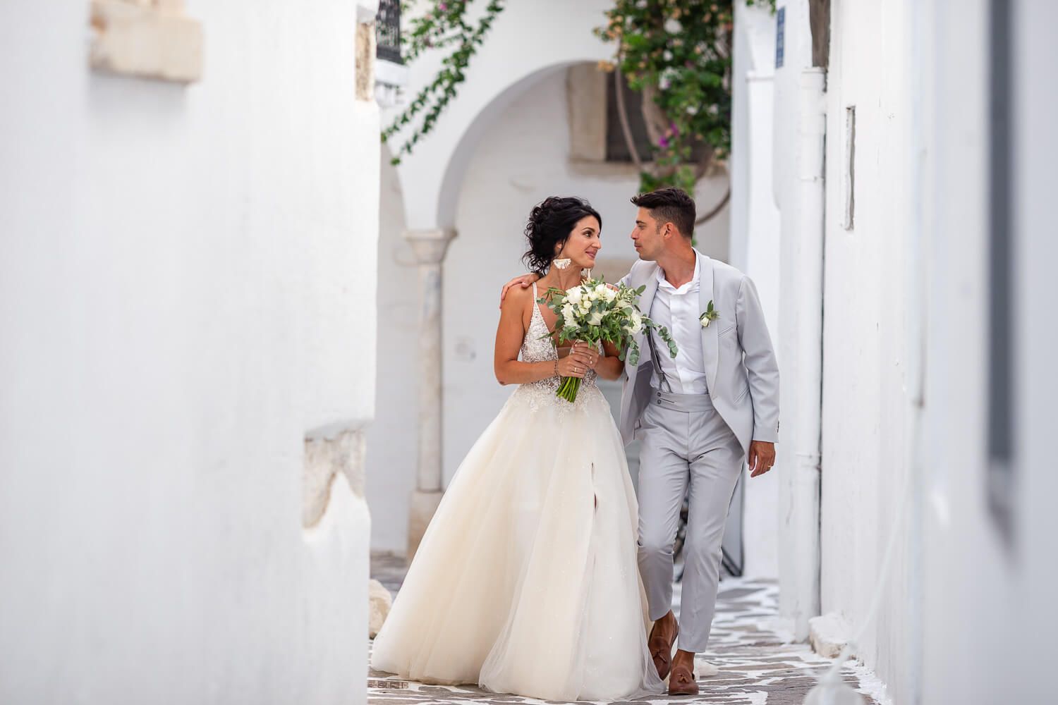 Candid stroll of the newlyweds holding hands in the old town of Parikia
