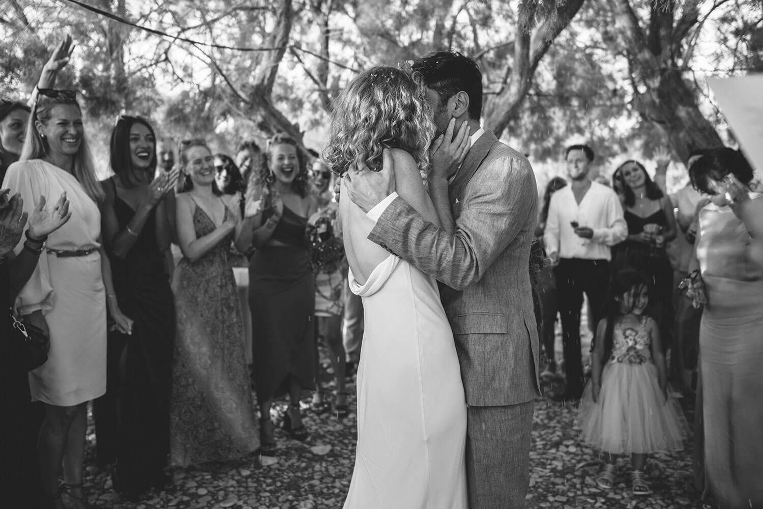 The newlyweds sharing their first kiss on the beach in Paros