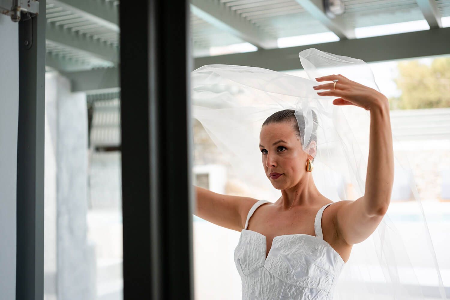 Bride putting on her dress with the help of her friends in Paros