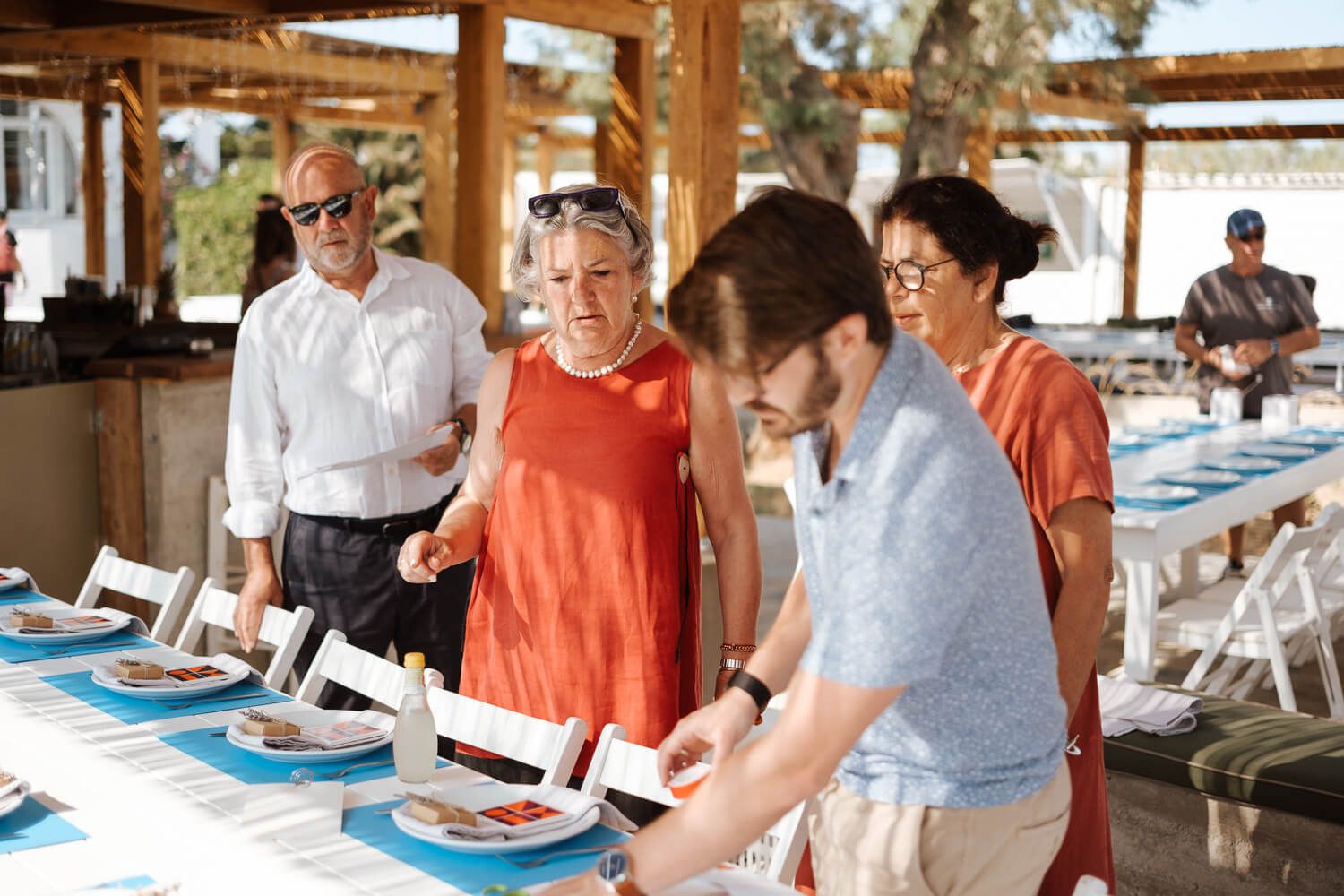 Wedding reception decor and table settings being prepared by guests and family at Rebel Bar Paros.