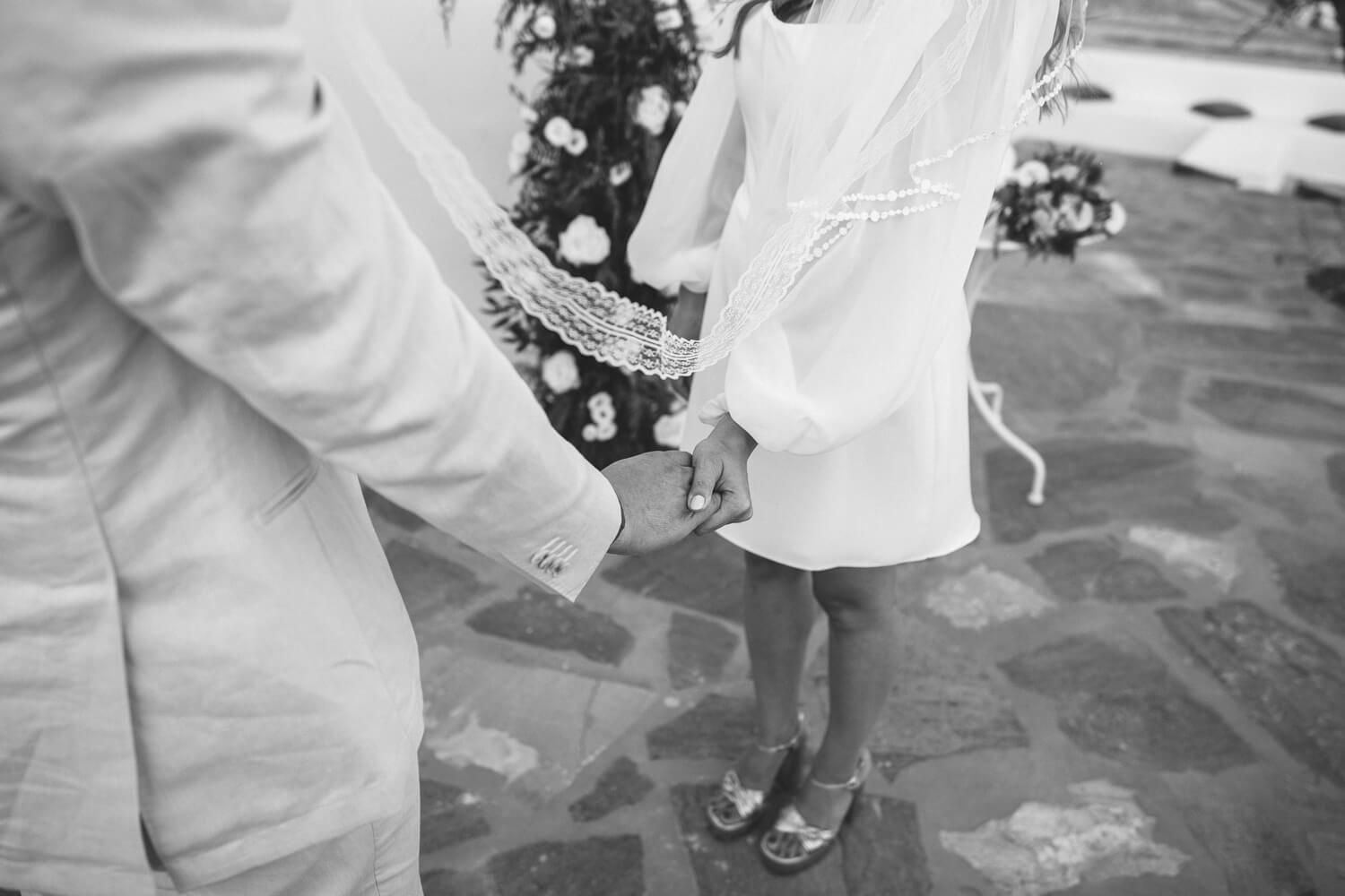 Bride and groom holding hands during their heartfelt symbolic vows in Greece