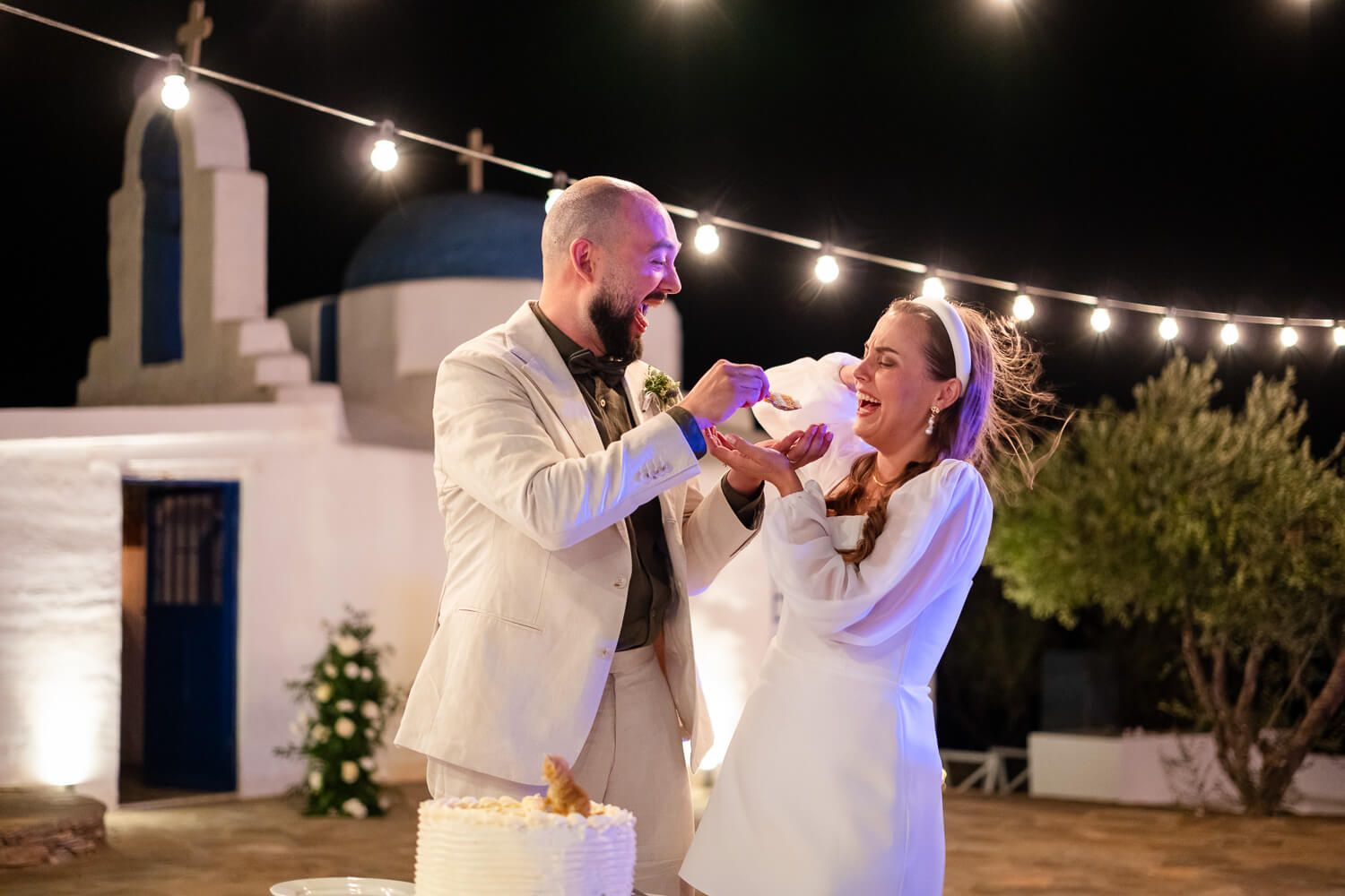 Couple sharing wedding cake during a wedding reception in Paros