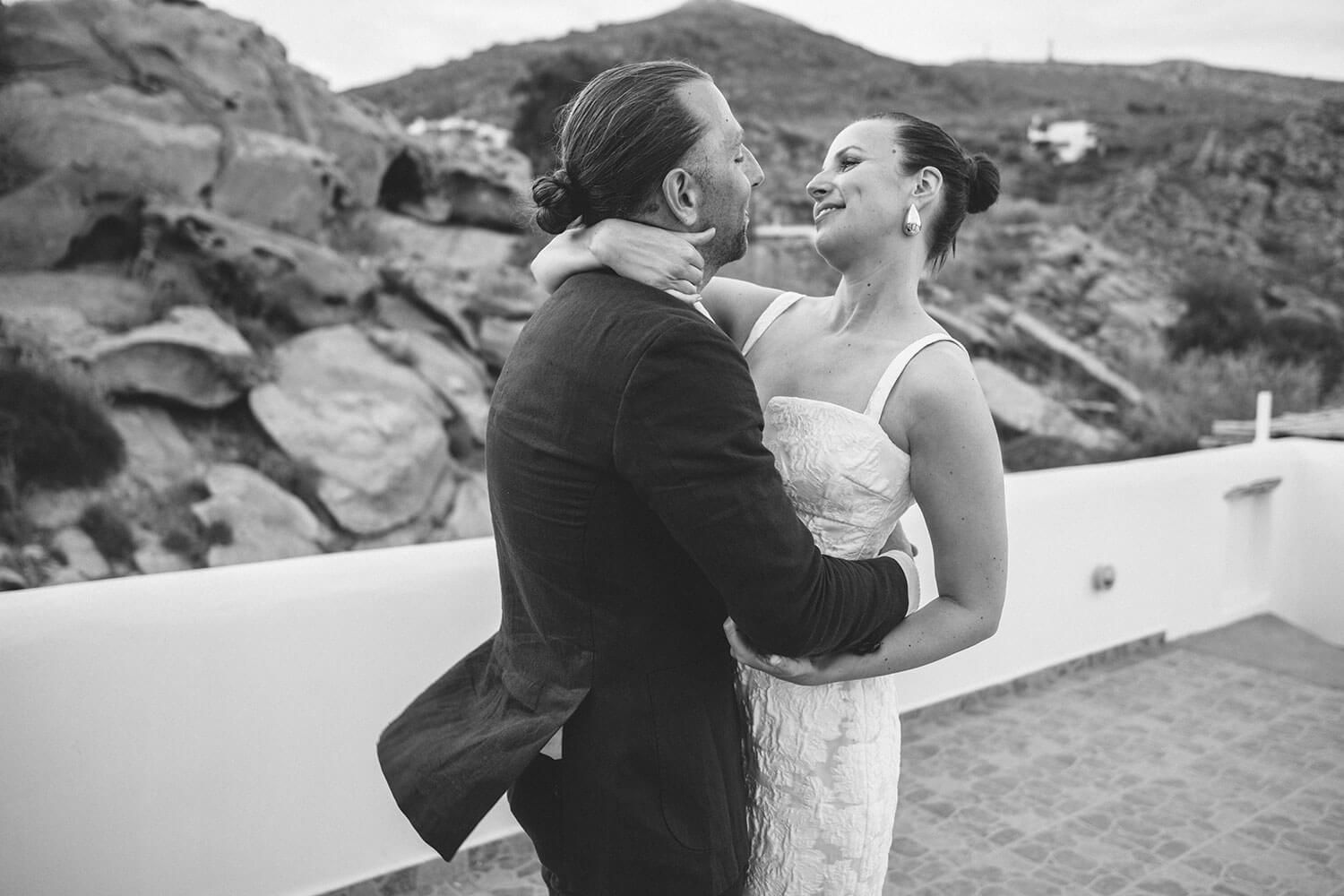 Newlyweds dancing on the rooftop with the Aegean sea behind them