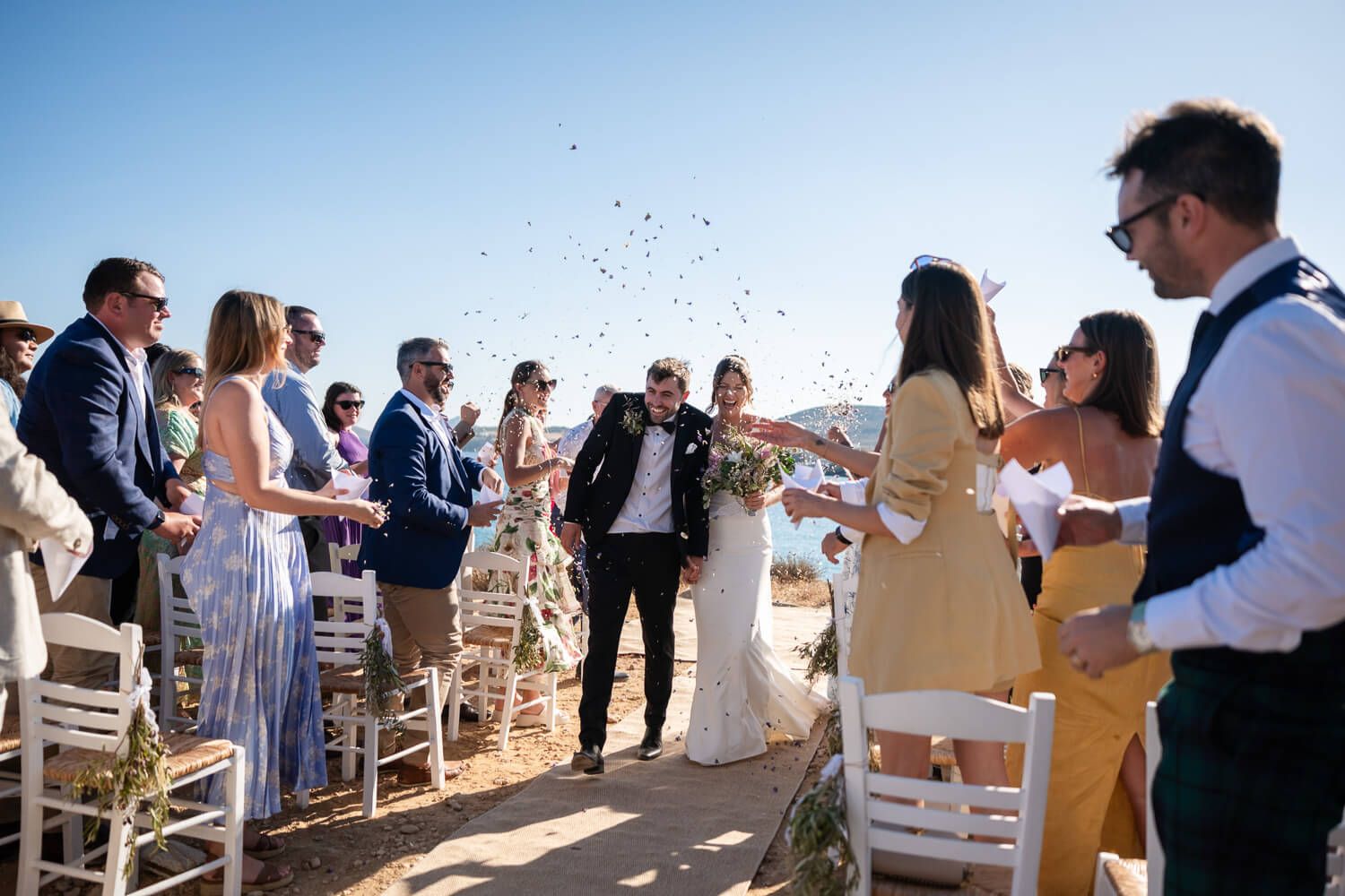 Joyful newlyweds walking through a shower of rice and rose petals