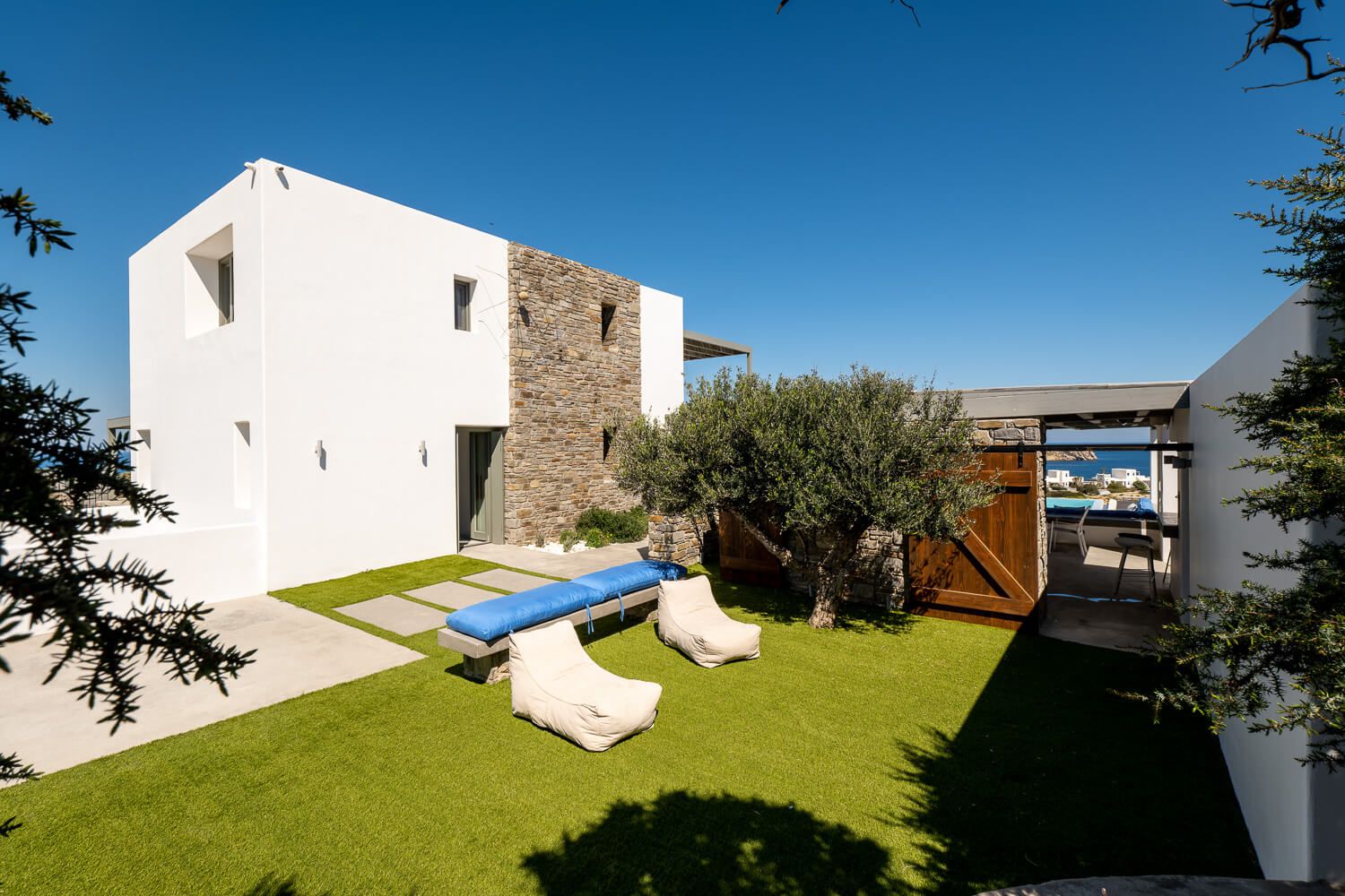 Modern white architectural structures with clean lines stand against a bright blue sky on a sunny day.