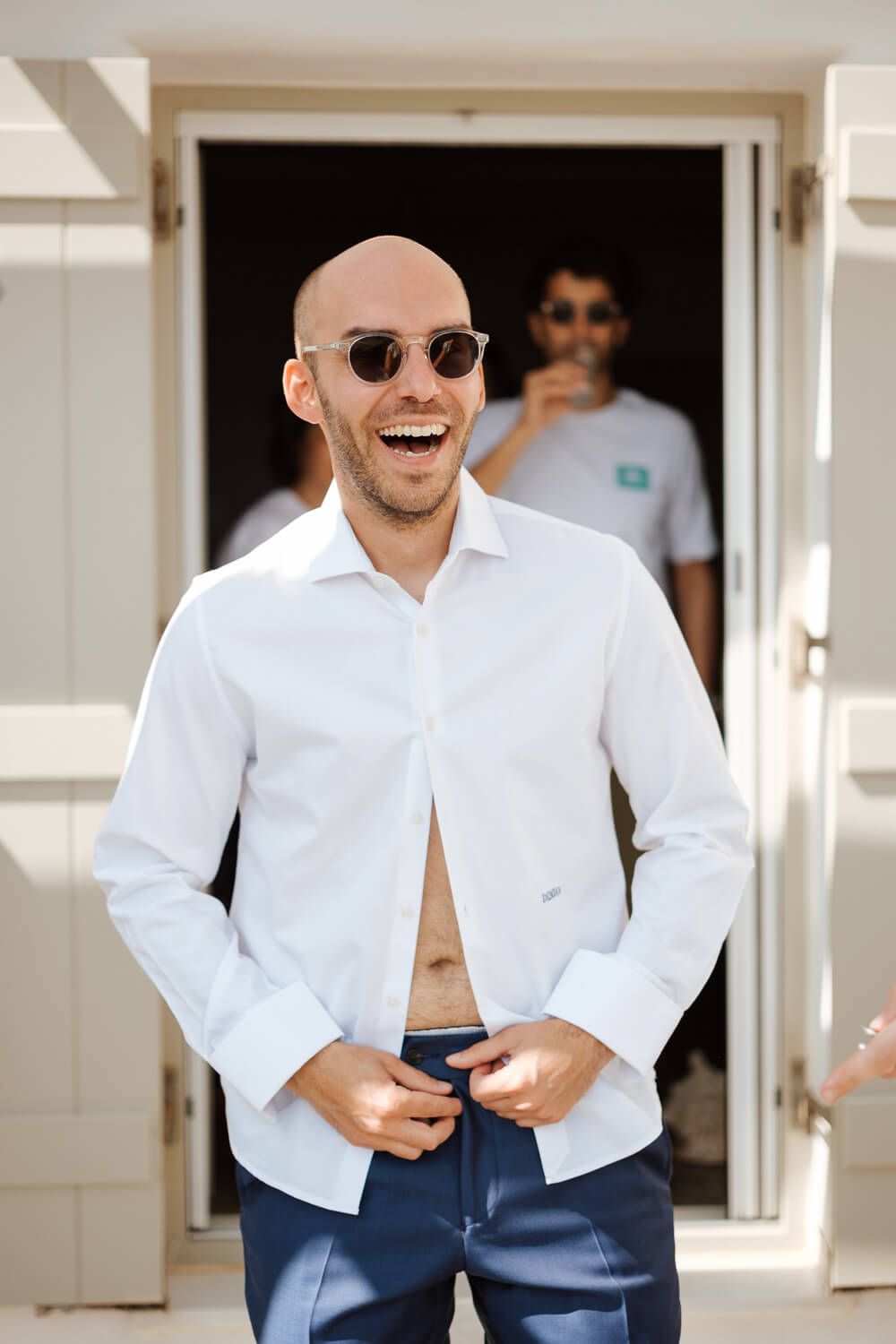 Groom Dimitris laughing while getting ready for the wedding in Golden Beach Paros