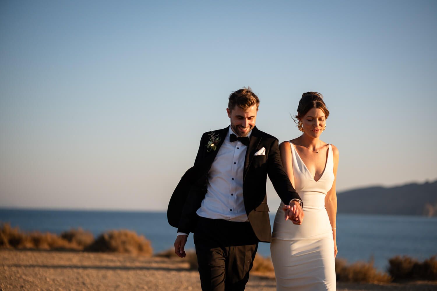Newlyweds walking hand in hand after their wedding ceremony during golden hour in Paros.