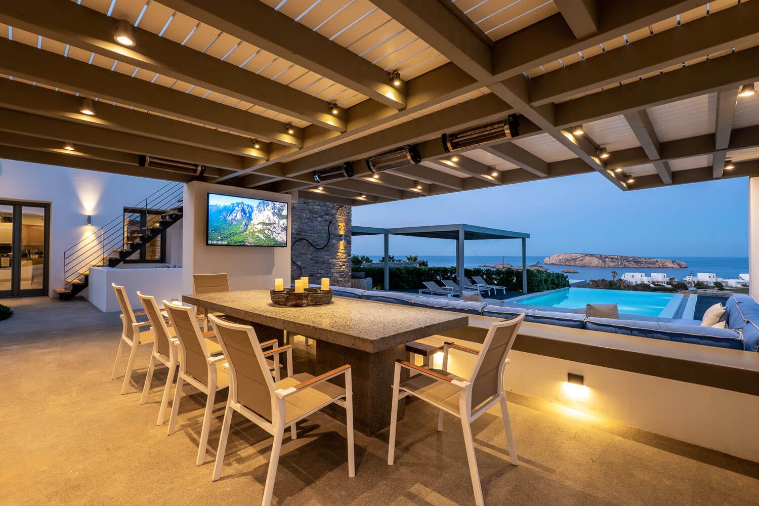 Modern outdoor dinining area with exposed wooden beams, pendant lighting and ocean views to the sea
