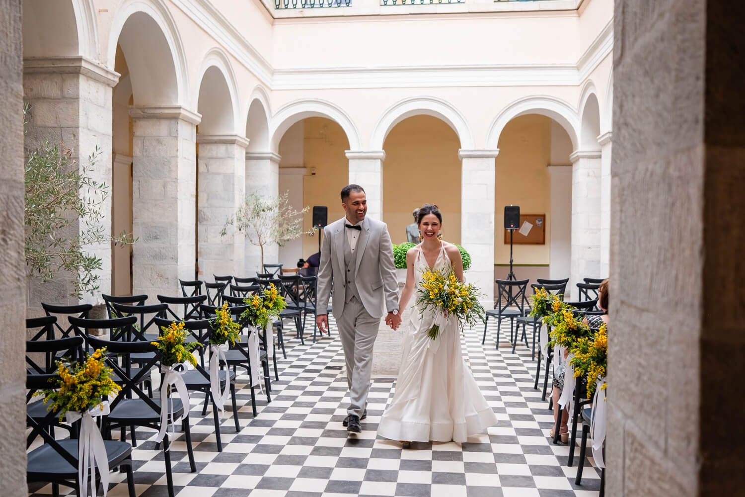 The couple holding hands under the beautiful town hall arches