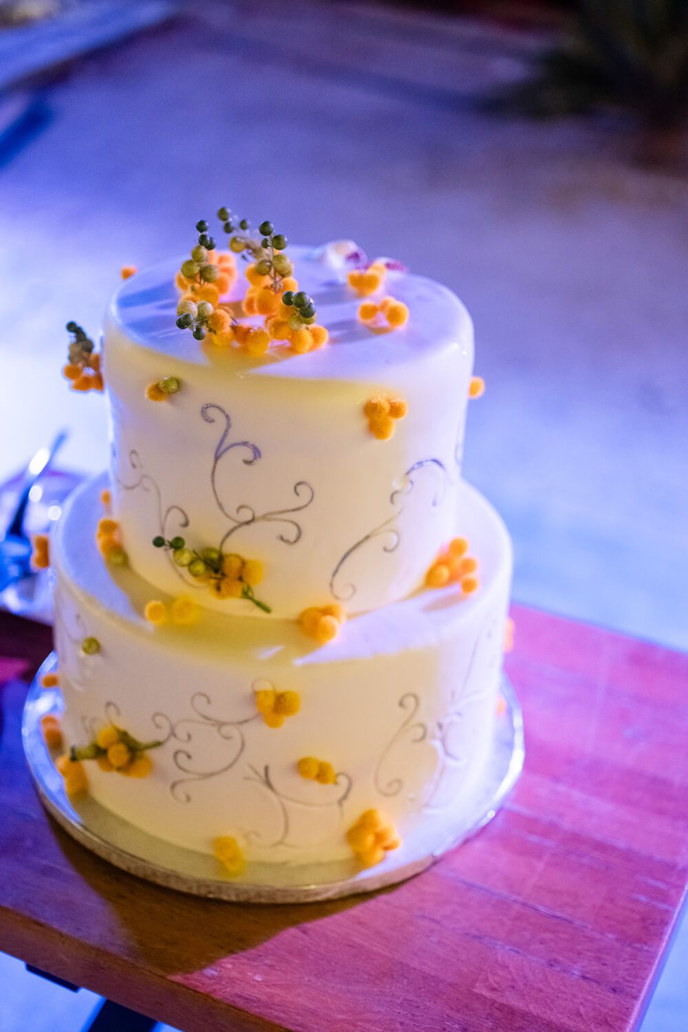A white wedding cake decorated with delicate swirls and orange floral accents.