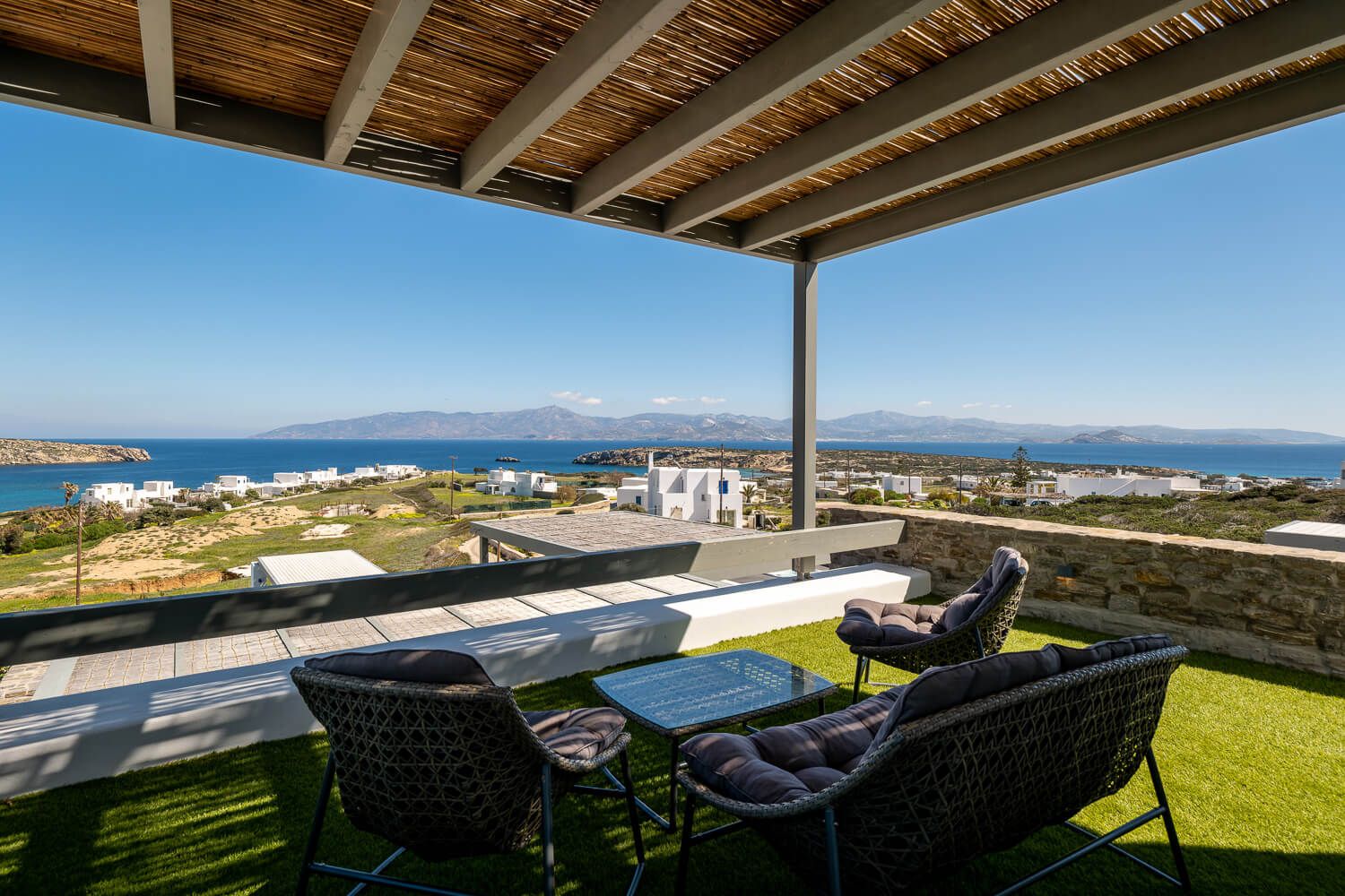 Luxurious outdoor patio with wicker furniture overlooking a stunning coastal view and blue Mediterranean waters.
