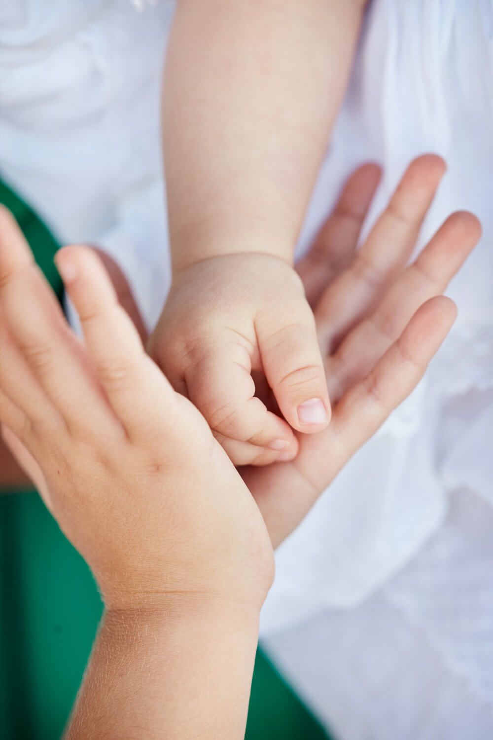 Close-up of a baby's tiny hand resting gently on an adult's open palm during a baptism in Greece.